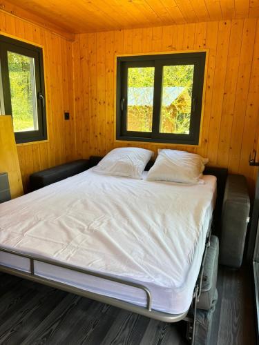 a bed in a room with two windows at Tiny house chalet montagnard in Arcizans-Dessus