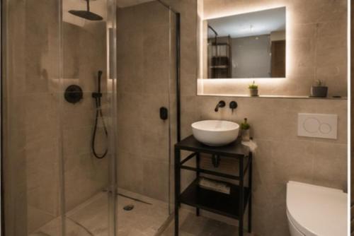 a bathroom with a sink and a shower with a mirror at APARTÉ HOTEL Dijon Sud in Chenôve