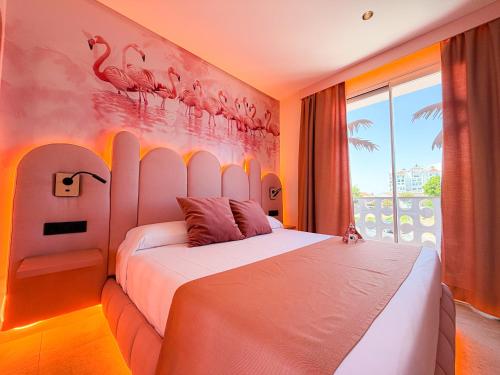 a bedroom with a bed with flamingos on the wall at On Pink Motel in Matalascañas