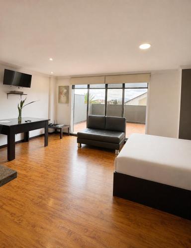 a bedroom with a bed and a couch and a desk at Gaviota Apartments & Suites in Cuenca