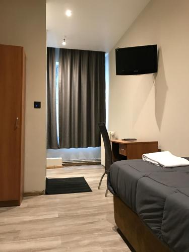 a bedroom with a bed and a desk and a television at Royal Hotel in Brussels