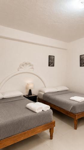 two beds in a white room with two tables at Hotel Casa Xicun in Tepoztlán