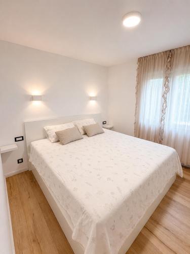 a white bedroom with a large bed with white sheets at Apartment Puntamica in Zadar
