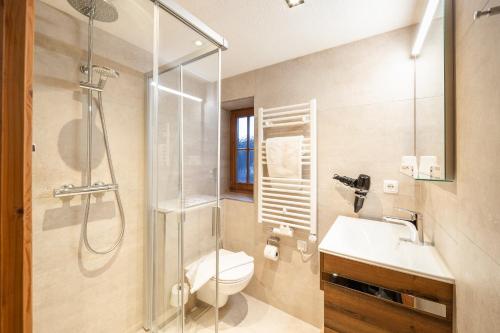 a bathroom with a shower and a toilet and a sink at Landhotel Vordergrub in Kitzbühel