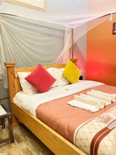 a bed with four colorful pillows on it at Kisoro Suits in Kisoro