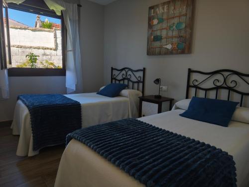 a room with two beds with blue pillows and a window at Apartamentos Mareventus in Sanxenxo