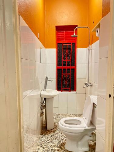a bathroom with a toilet and a red window at Kisoro Suits in Kisoro