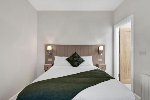 a bedroom with a large white bed with a green blanket at Millmaster Apartment in Drumahayre
