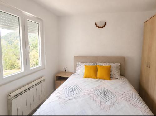 a bedroom with a bed with two yellow pillows at Rural Household Baltic in Mojkovac