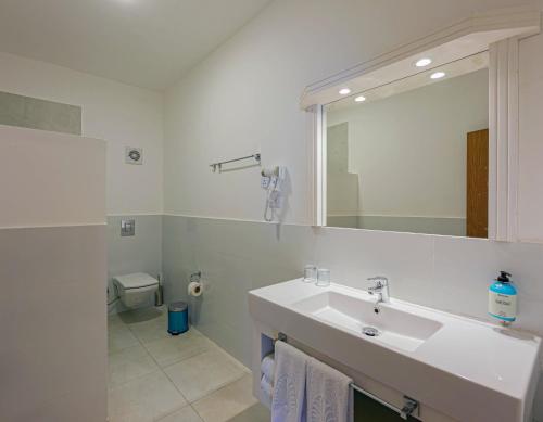 a white bathroom with a sink and a toilet at Royal Brayka Beach Resort in Marsa Alam City