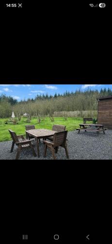 a picnic table and two benches in a field at The Mid Devon Retreat in Crediton