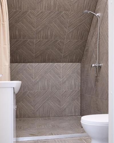 a bathroom with a brown tiled wall at Jūros terasos in Šventoji