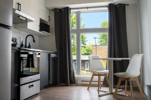 a kitchen with a table and two chairs and a window at Appart'hôtel Vivéo - Par Aneyro in Quebec City