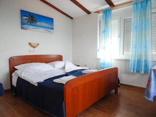 a bedroom with a bed with blue curtains and a window at Guest House Frane in Pag