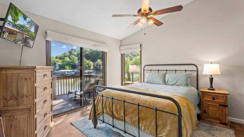 a bedroom with a bed with a fan and a balcony at Honey Hole 3 Well Dock in Camdenton