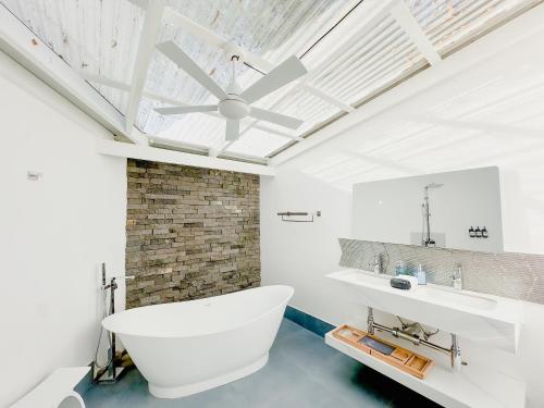 ein Badezimmer mit weißer Badewanne und Deckenventilator in der Unterkunft T Loft in Playa Hermosa