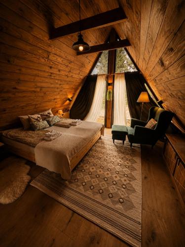 a bedroom with a bed and a chair and a window at Grzeszne Chatki - Smerek in Smerek