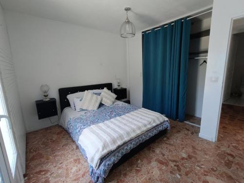 a bedroom with a bed with a blue curtain at Maison Éléphantaisie in Salies-de-Béarn