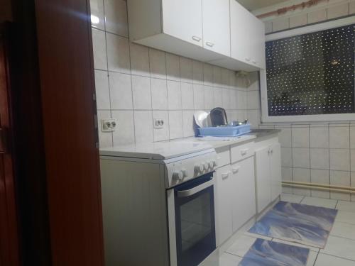 a kitchen with white cabinets and a sink and a stove at Apartman Bistrivoda 2 in Vogošća