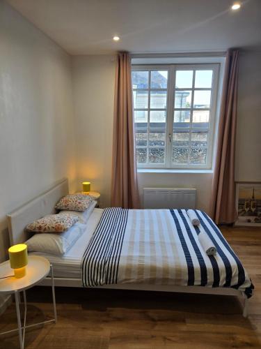 a bed in a bedroom with a window and two tables at Studio moderne en hyper-centre de Vendôme in Vendôme