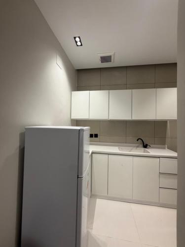 a kitchen with white cabinets and a refrigerator at شقق الحصن الفاخره in Al Baha