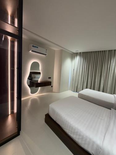 a white bedroom with a bed and a window at شقق الحصن الفاخره in Al Baha