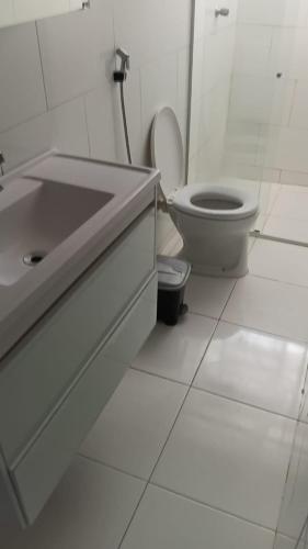 a white bathroom with a toilet and a sink at Casa da Floresta in Vitória