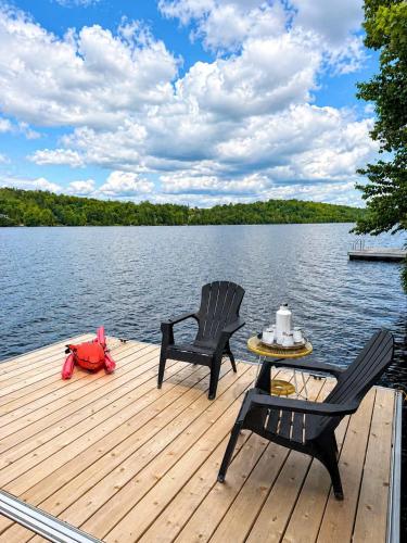 a dock with two chairs and a table on a lake at Waterfront & Nature - Chalet Lac Clair in Entrelacs