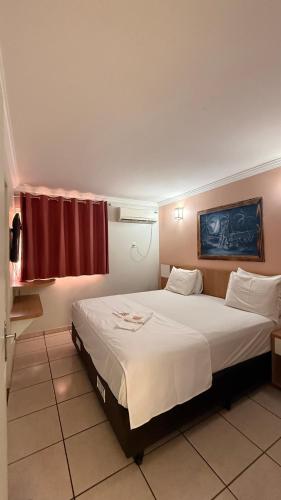 a bedroom with a large bed with a red curtain at Nobrezafiori Diroma FIORI taxas de Roupas de Cama Banho e taxas do hotel valor a pagar na recepcao do hotel OBS MENOR DE 18 anos desacompanhado dos pais tem que ter autorizacao com RECONHECIMENTO de firma no cartório in Caldas Novas