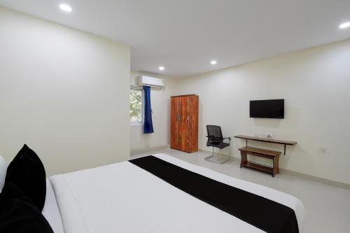 a bedroom with a bed and a desk and a television at Hotel O Sree Nirvi in Ameerpet