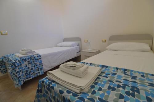 two beds in a room with towels on a table at Loredana's House in Pachino