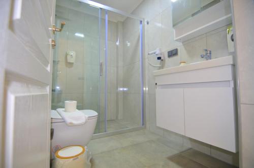 a white bathroom with a shower and a toilet at Fethiye Cagri Pansiyon in Fethiye