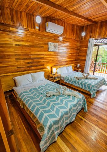 two beds in a room with wooden walls at Jacaranda House, rustic, Private Pool in Talamanca