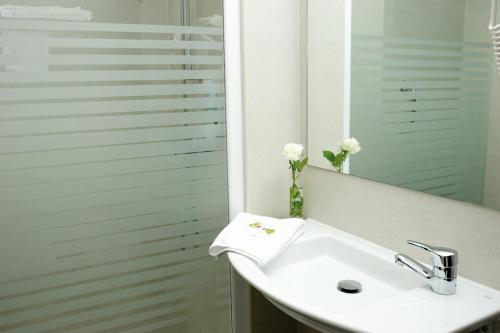 a white sink sitting under a mirror in a bathroom at Hotel Cisneros in Alcalá de Henares