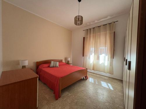 a bedroom with a red bed and a window at La casa di GiòGiò in San Vito lo Capo