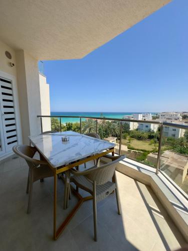 a table and chairs on a balcony with a view at Apartment with sea view and pool access in Chott Meriem