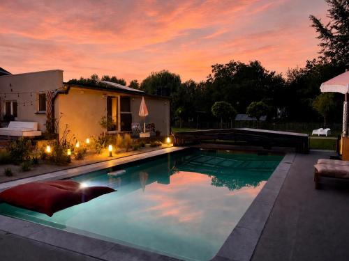 a swimming pool in front of a house with a sunset at Chambre d Amis in Lokeren