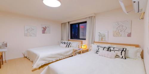 two white beds in a room with a window at Uffice apartment in Shanghai