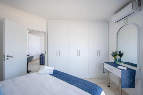 a white bedroom with a bed and a mirror at Hibernian Towers 408 in Strand