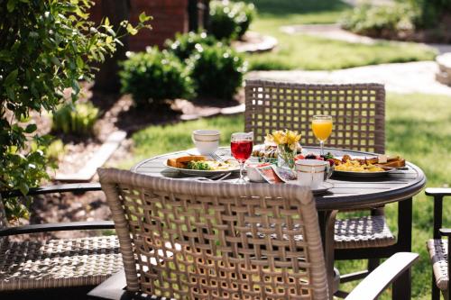 a table with plates of food and two glasses of wine at The Edenton Collection – Captain’s Quarters Inn in Edenton
