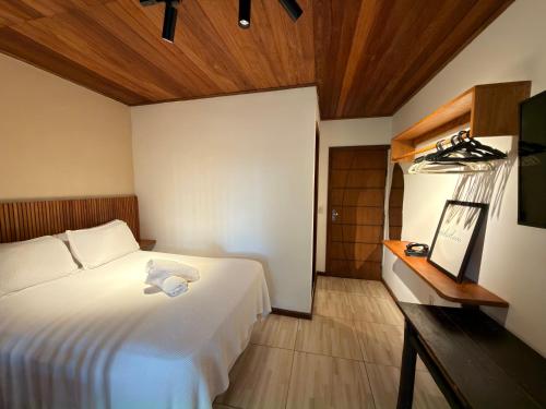 a bedroom with a white bed and a wooden ceiling at Pituba Vile - Apartamento Jardim in Itacaré