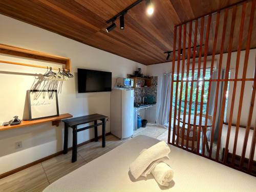 a living room with a table and a refrigerator at Pituba Vile - Apartamento Jardim in Itacaré