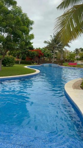 a large blue swimming pool with trees in the background at Zill Hawana in Ma‘mūrah