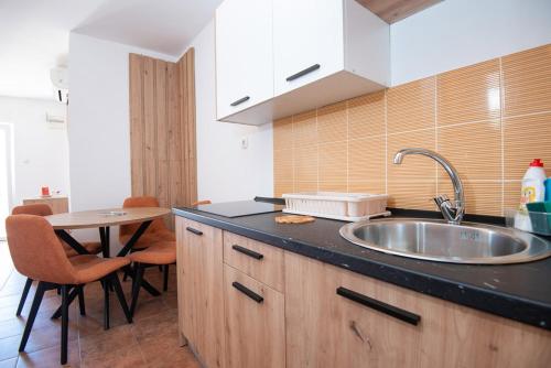 a kitchen with a sink and a table with chairs at Apartment Veslo in Begovići