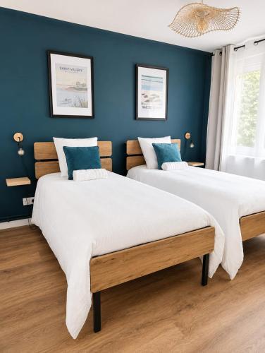 two beds in a bedroom with blue walls at La petite maison secrète in Abbeville