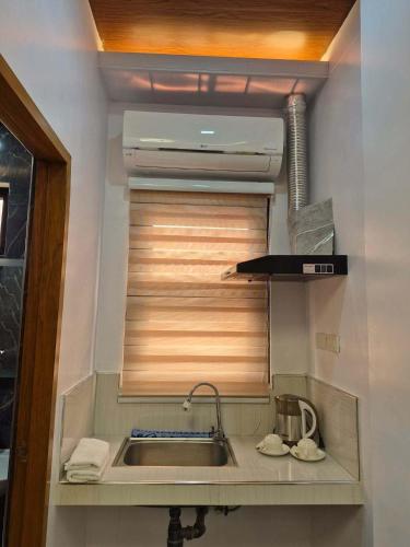 a kitchen with a sink and a blind over a window at Silid in Legazpi