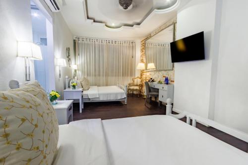 a white bedroom with a bed and a desk and a room at Hotel Monaguillo de Getsemaní in Cartagena de Indias