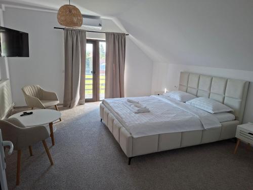 a bedroom with a large white bed and a table and chair at Casa Nițică in Vaslui