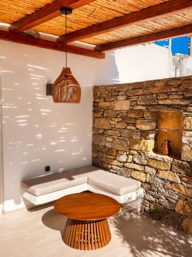 a room with a couch and a table and a stone wall at Anastasia's Luxury Suite with jacuzzi in Angairiá