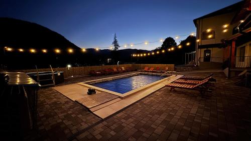 a swimming pool with a bench and lights around it at Casa Basarab in Călimăneşti